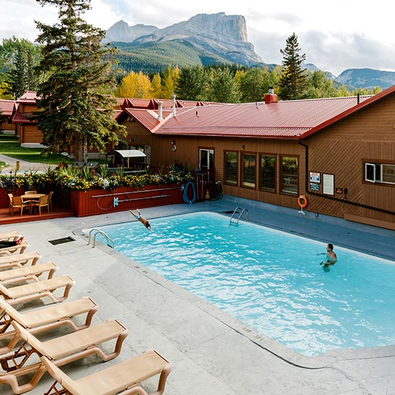 An outdoor swimming pool between wooden cabin buildings.